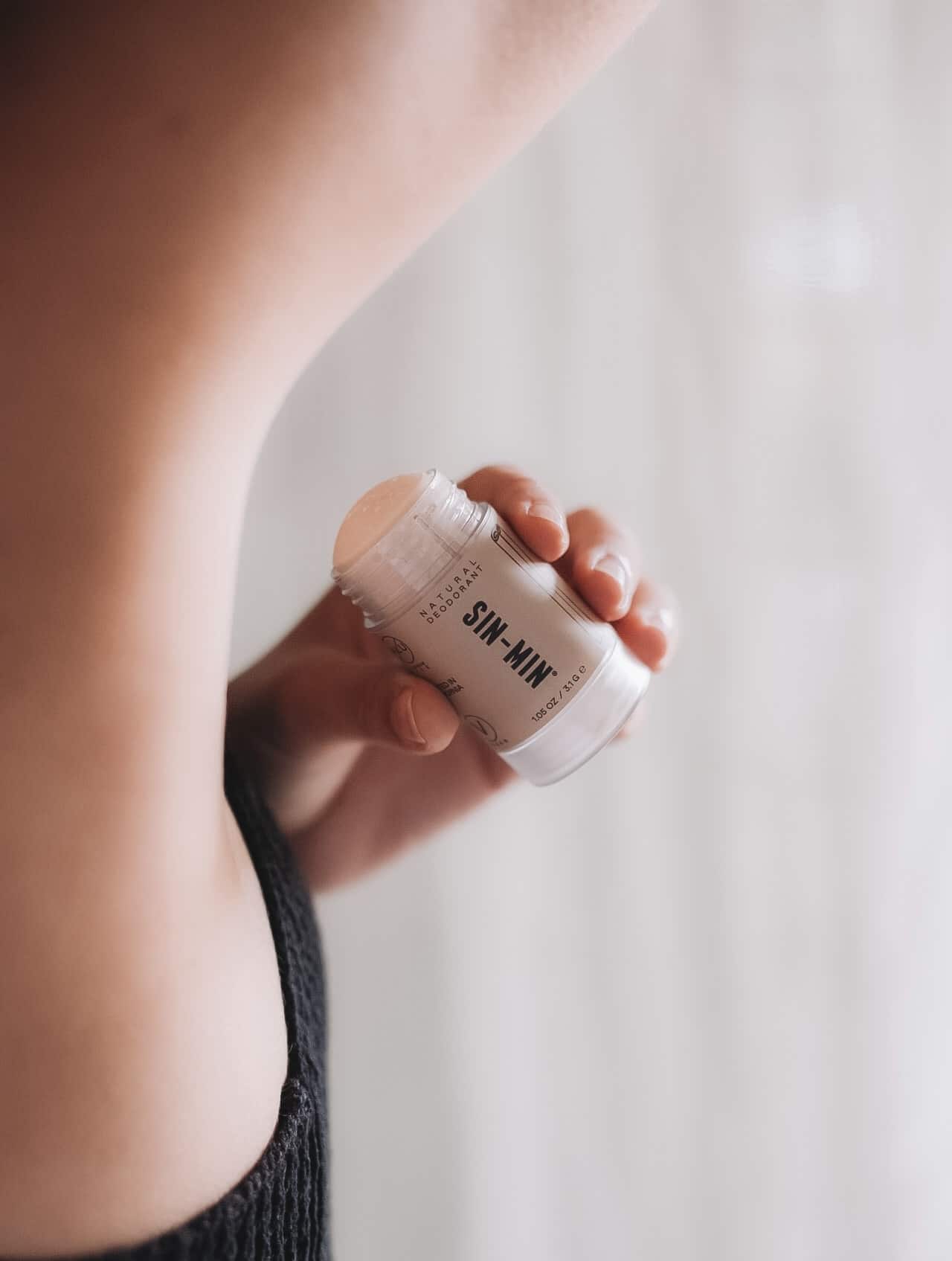Model holding a Natural Deodorant in her hand placed under her arm.