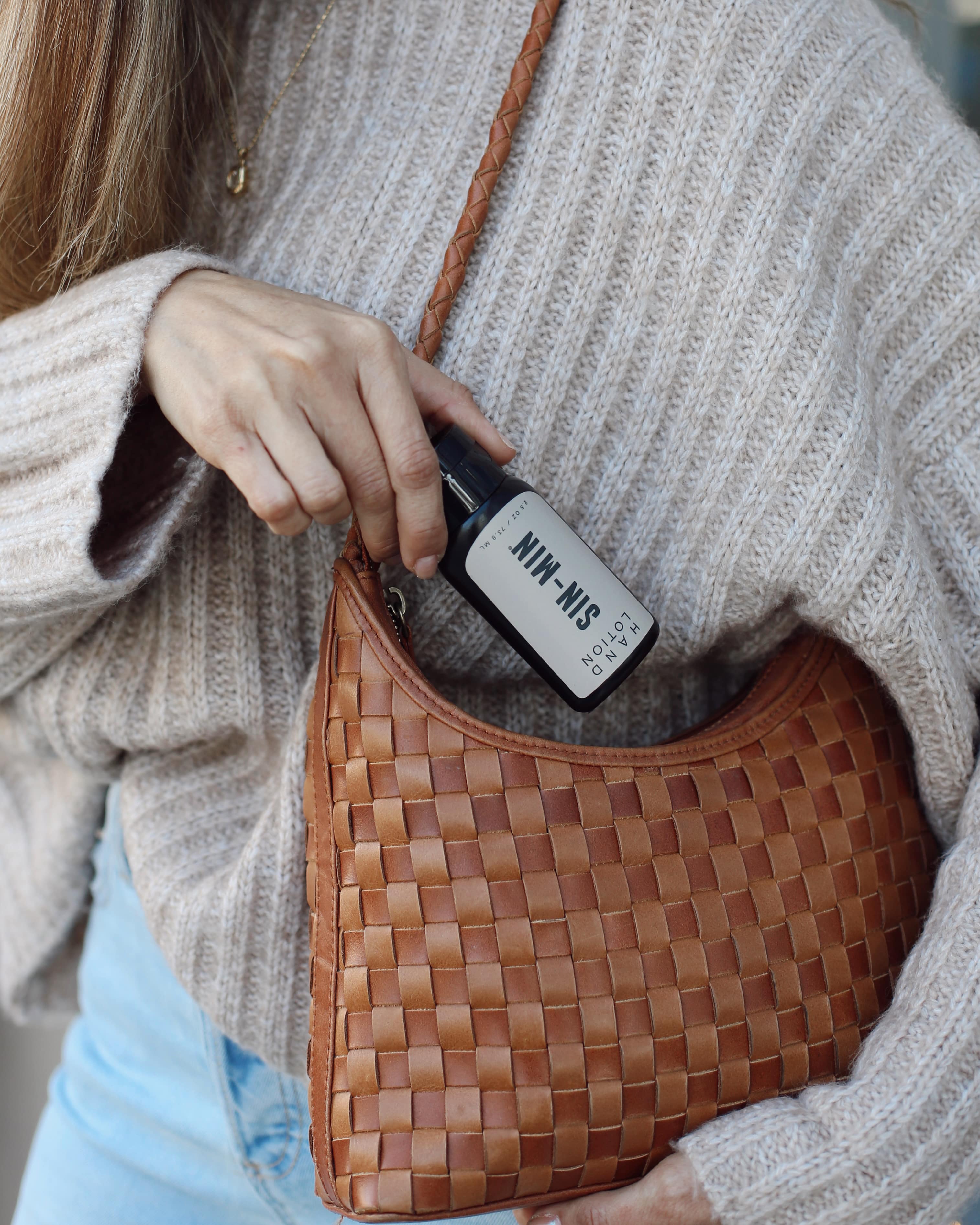 Model putting hand lotion into purse