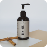 Body lotion bottle with pump on a white surface and beige background