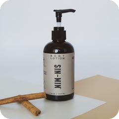 Body lotion bottle with pump on a white surface and beige background