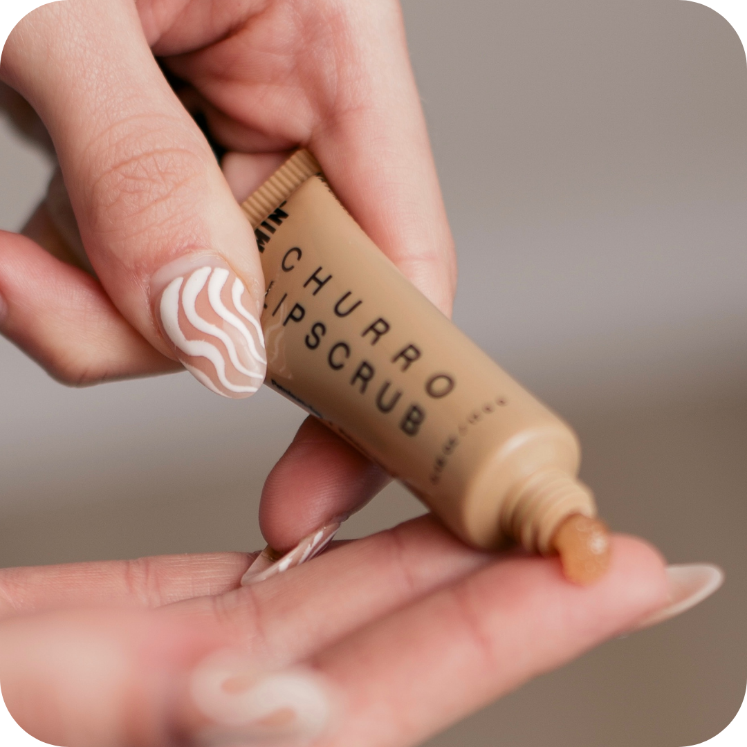 Hand holding a tube of 'Churro Lipscrub' with a blurred background
