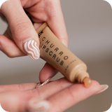 Hand holding a tube of 'Churro Lipscrub' with a blurred background
