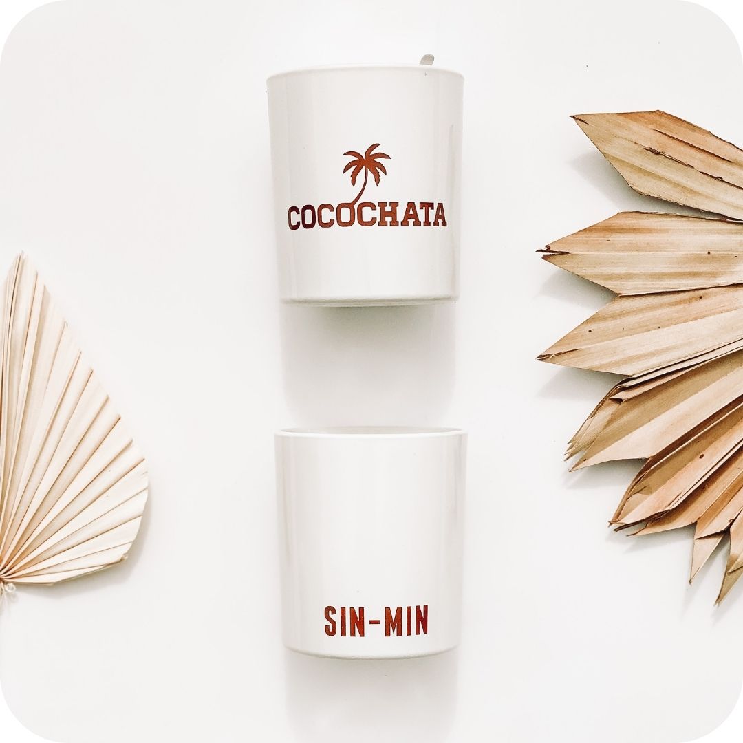 Image of 2 cocochata candles on a white studio background with dried palm fronds on the left and right sides