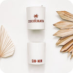 Image of 2 cocochata candles on a white studio background with dried palm fronds on the left and right sides