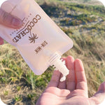 Close up of Cocochata being dispensed into models hands with sandy hills in the background