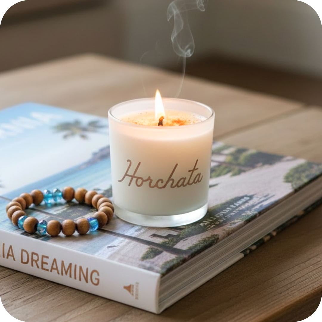 Candle labeled 'Horchata' on a book with a wooden beaded bracelet.