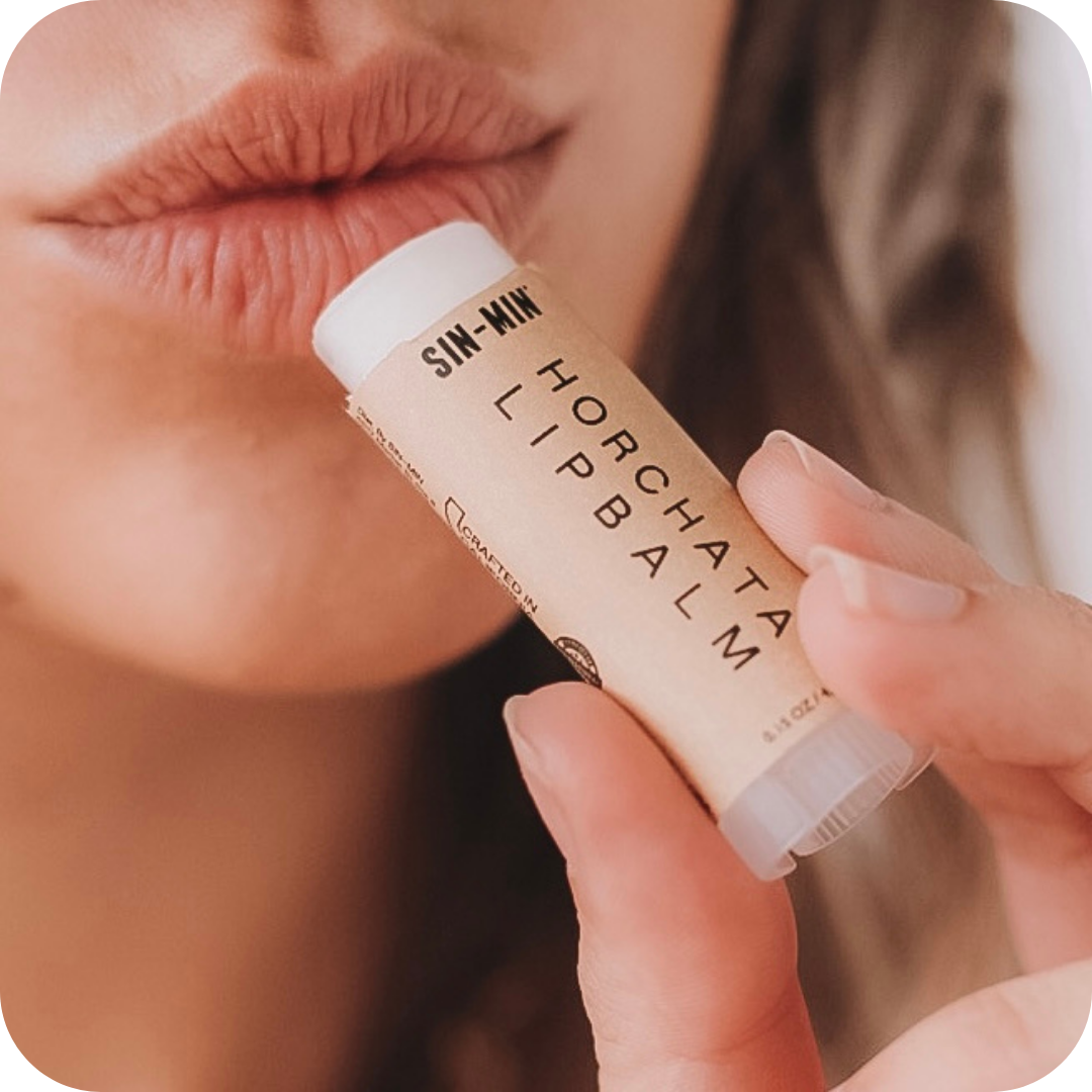 Person applying a lip balm labeled 'Horchata' to their lips.