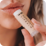 Person applying a lip balm labeled 'Horchata' to their lips.