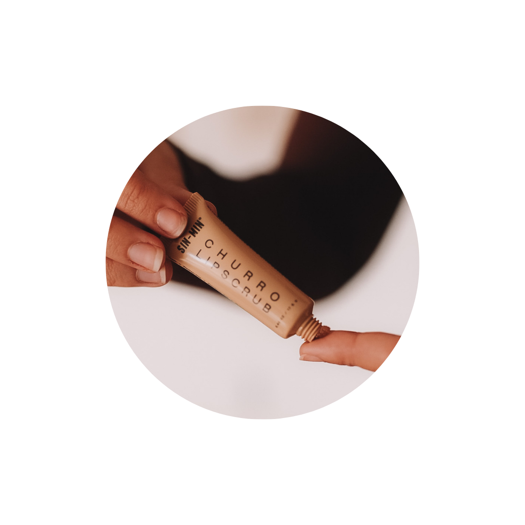 Picture of SIN-MIN churro lip scrub being held by model's hands