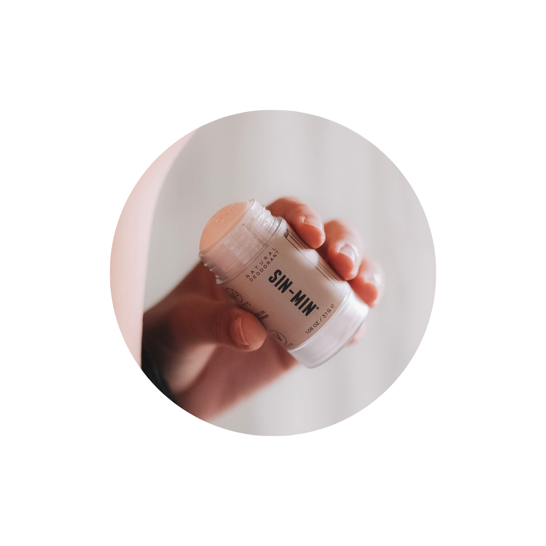 natural deodorant with the top off being held by hand model