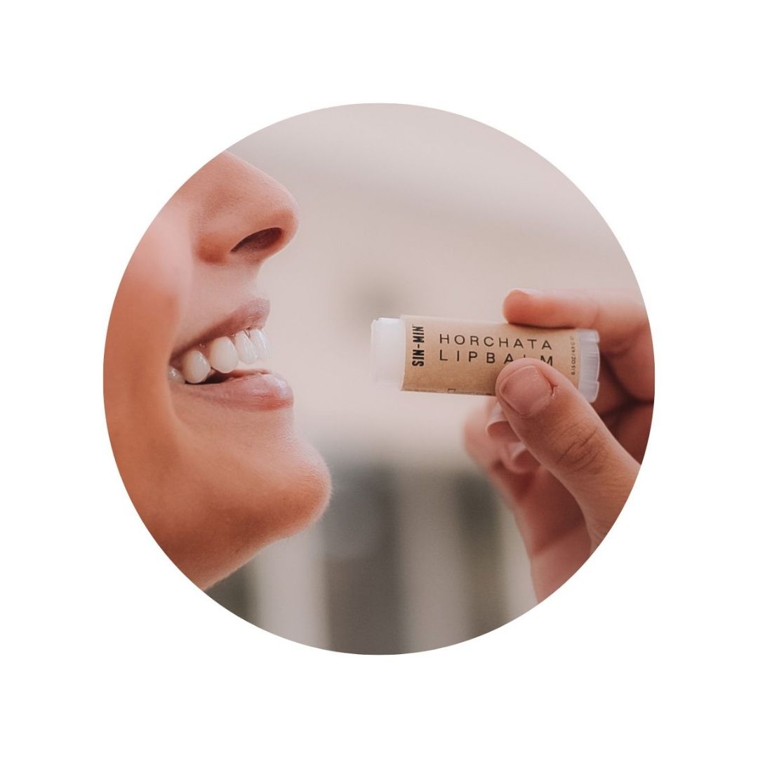 Woman putting on Horchata Lip Balm and smiling