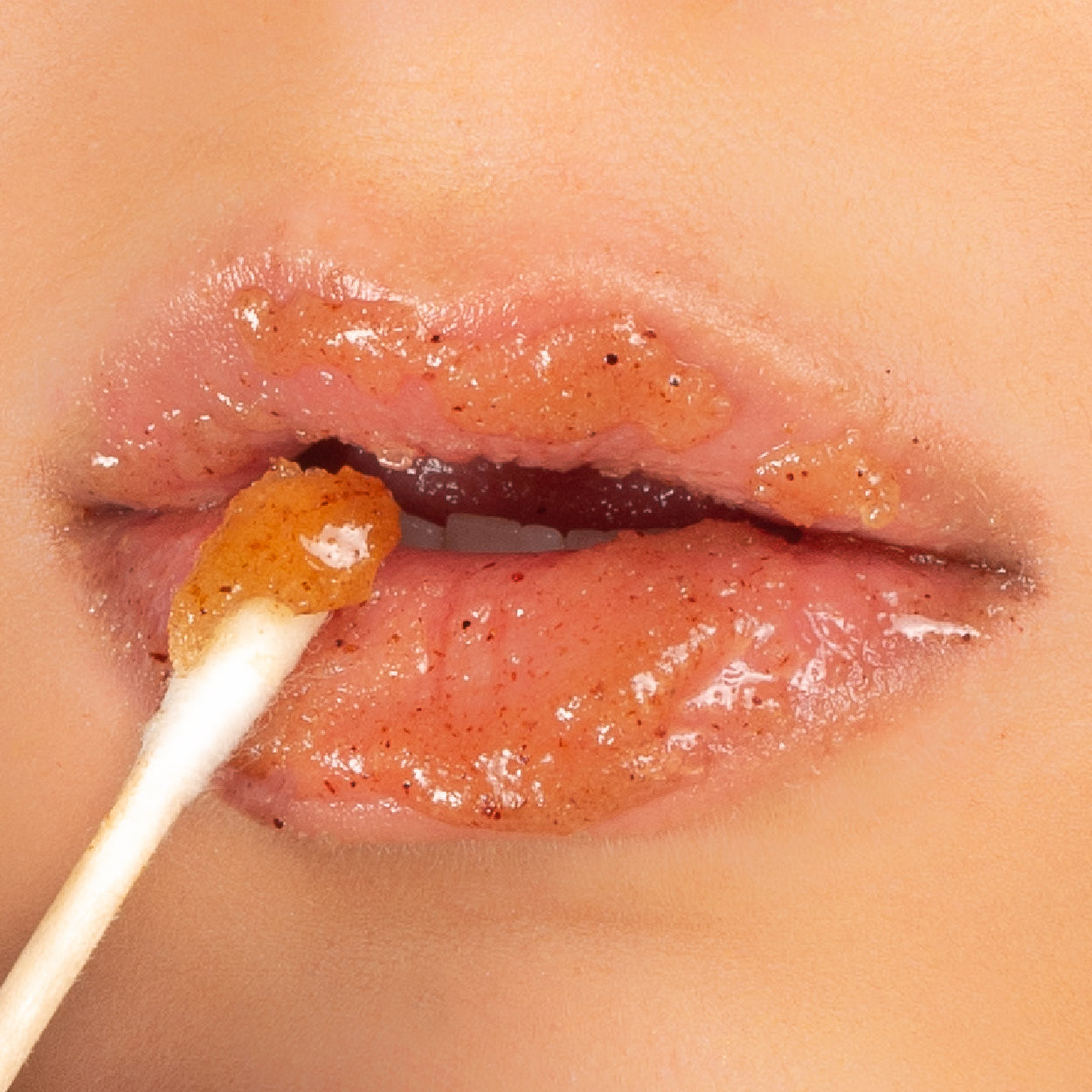 Close up picture of lips with a q-tip spreading Churro Lip Scrub on them